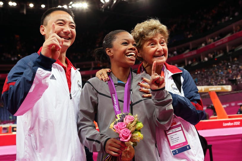 Gabrielle Douglas of the United States celebrates winning the gold medal with coach Liang Chow and team coordinator Martha Karolyi after the Artistic Gymnastics Women's Individual All-Around final on Day 6 of the London 2012 Olympic Games at North Greenwich Arena in London, England on August 2, 2012